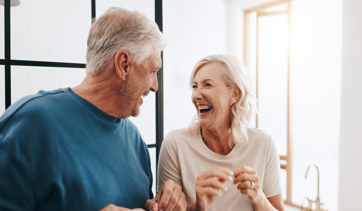 Happy elderly couple smiling and laughing after receiving gentle dental care.