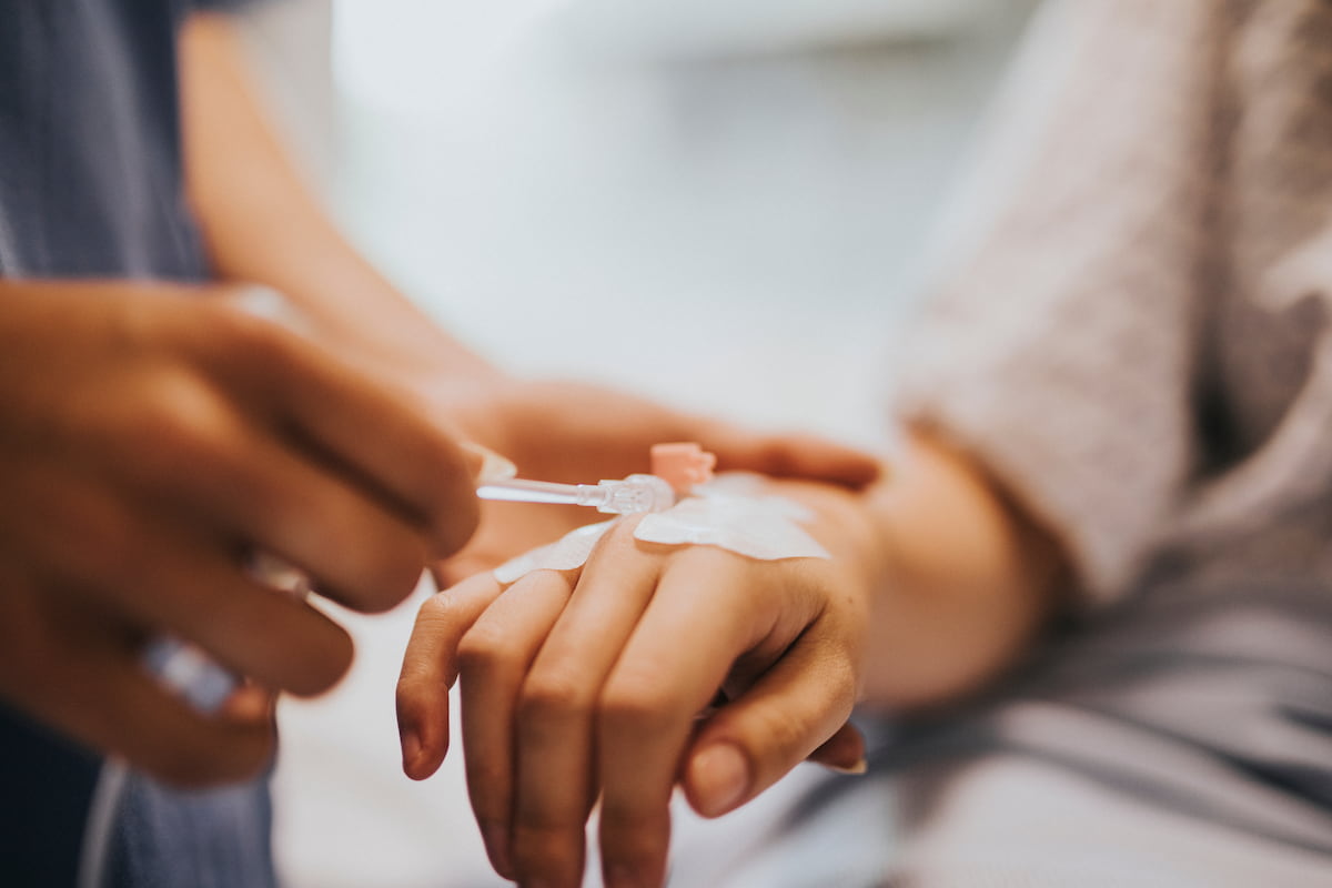 Close-up of an IV drip being inserted into a patient’s hand before sedation for dental treatment.