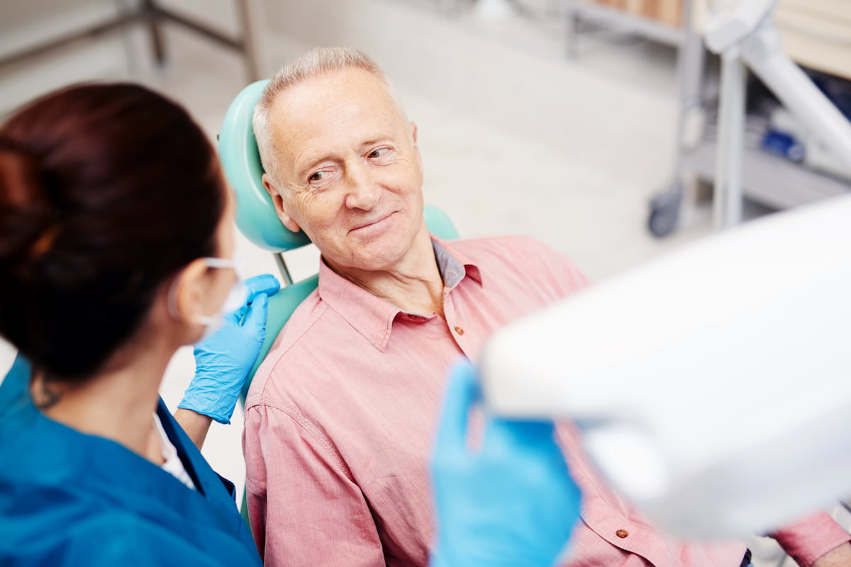 Elderly man receiving dental care during an oral health check with a dentist.